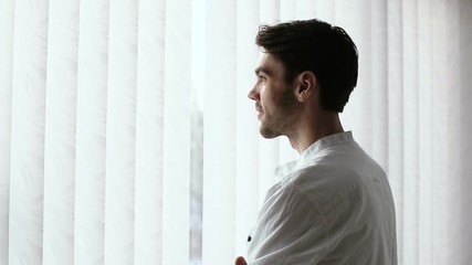 A man standing in half a turn and starts smiling