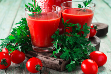 Glasses of tomato juice with vegetables on wooden background, healthy drink
