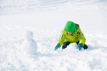 Fototapeta na wymiar Child building a snowman