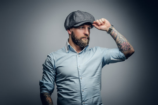 Bearded male in a shirt and tweed cap.