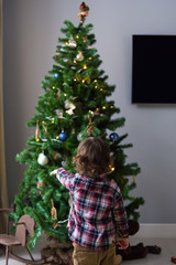 Little boy dresses up a Christmas tree at home