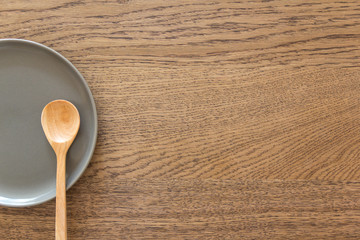 half grey empty  plate with a spoon on wood table