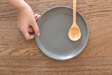 wood spoon on dark grey plate holding by female hand