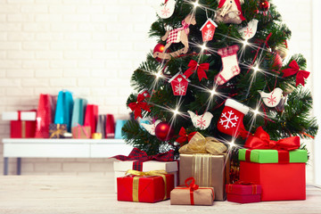 Fototapeta na wymiar Christmas tree with present boxes over white brick wall