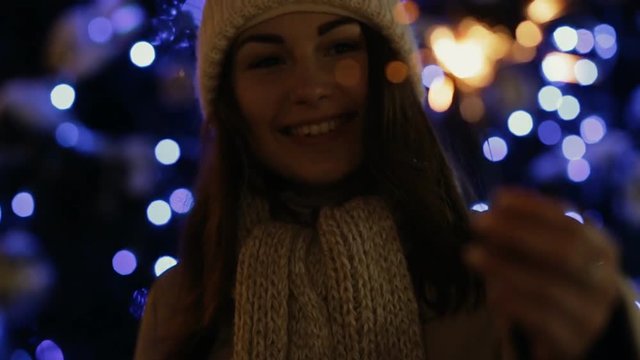 Woman in winter enjoying with a sparkler in city, slow motion.