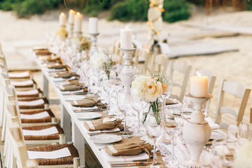 Long dinner table decorated with flaxen cloth and white candles