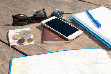 Preparation for travel,trip vacation, tourism mock up of cell phone, passport, money,sunglasses,road map, notebook ,Essential vacation items on wooden table, Travel concept background