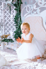 happy little girl in white dress standing in the Christmas decorated room
