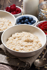 homemade oatmeal and berries on wooden table, vertical closeup