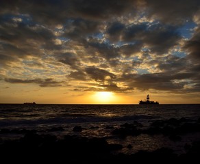 Amazing sunrise from the seashore with low clouds and oil rig in background