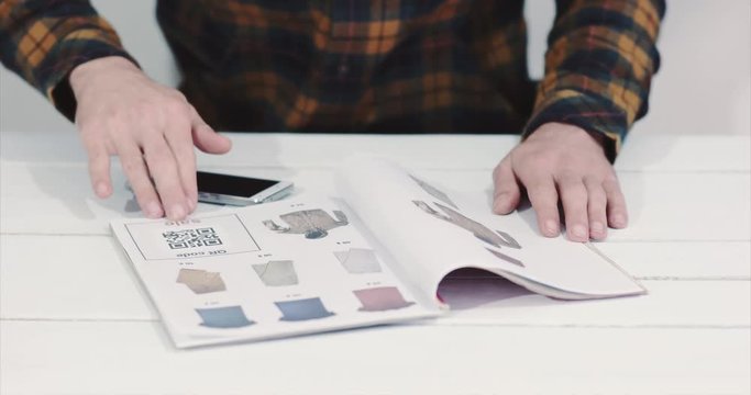 Man scanning qr code advertising with smartphone on clothes catalog modern technology and fashion shopping concept