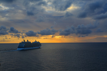 Cruise ship sailing on ocean during the sunset.
