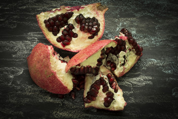 Pomegranate fruit cut in half on a dark background, showing red seeds. Healthy eating, diet or cooking concept. Vegan food. Raw food.
