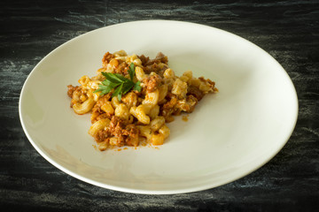 Pasta Carbonara. Spaghetti with bacon, parsel and parmesan cheese. Pasta Carbonara on white plate with parmesan on dark background. Italian food concept.