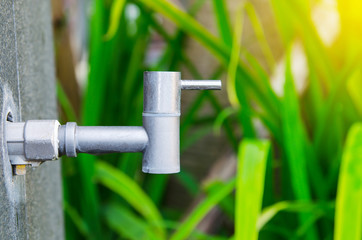 Water tap with water drop outdoor green park background