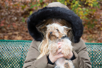 in autumn young blond girl playing with his lovely little dog