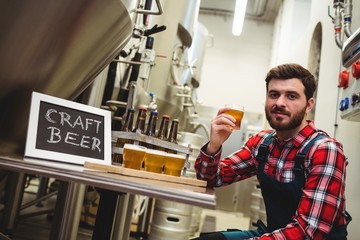manufacturer holding beer glass in brewery