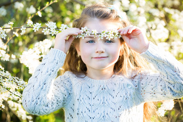 Portrait of a beautiful little girl with blossoming cherry wreat