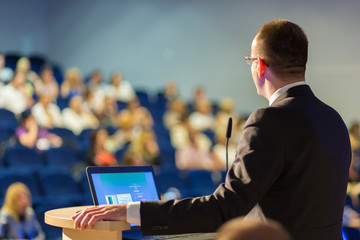 Speaker giving a talk on corporate Business Conference. Audience at the conference hall. Business...