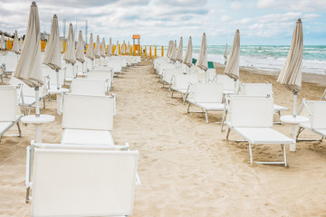 Rows of closed umbrellas and deckchairs on the empty beach