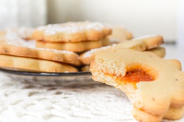 Homemade apricot jam Linzer bite with icing sugar on the white table close up