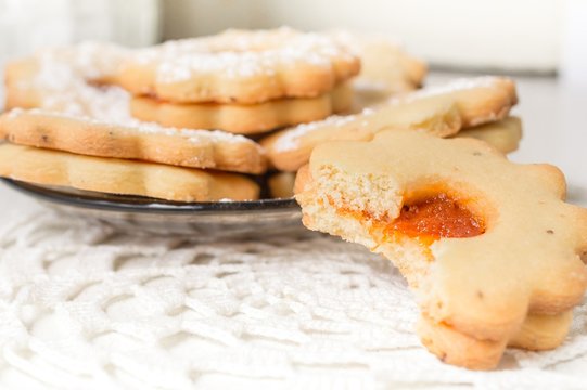 Homemade apricot jam Linzer bite with icing sugar on the white table close up