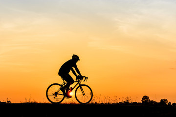 Obraz na płótnie Canvas Silhouette of cyclist motion on sunset background