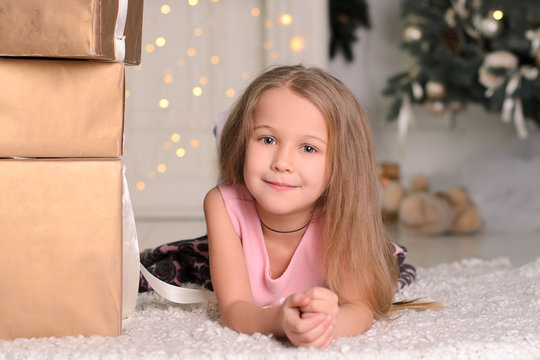 girl child with box of Christmas gift lying on floor