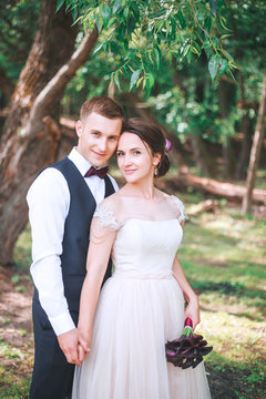 Groom and bride together. couple hugging. Wedding day. Beautiful bride and elegant groom walking after wedding ceremony. Luxury bridal dress and bouquet of flowers. Bride and groom at wedding day