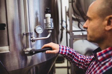 Manufacturer adjusting pressure gauge in brewery