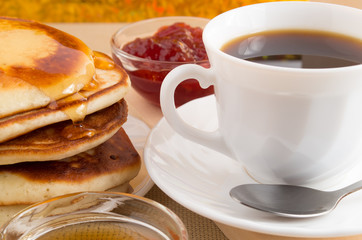 Pancake with honey, strawberry jam and a cup of coffee