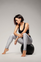 Beautiful sporty lady sitting on a fitness ball - obrazy, fototapety, plakaty