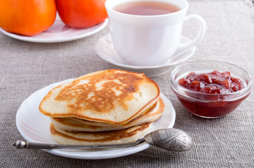 Pancakes with strawberry jam and cup of tea