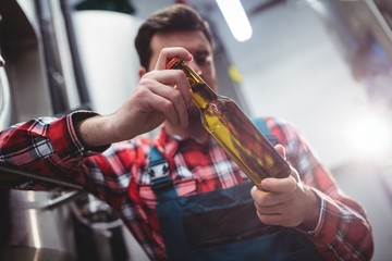 Manufacturer examining beer bottle at brewery