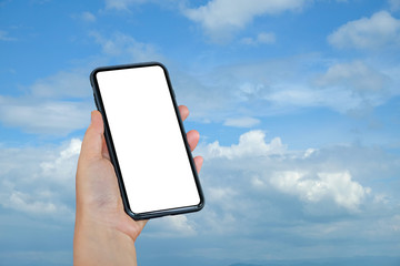 Smart phone in hand on blue sky background.