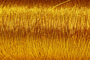 the spool of gold thread closeup horizontal