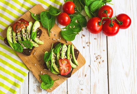 Toast with sliced avocado, tomatoes, spinach and spices