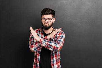 Serious man standing over chalkboard while make stop gesture
