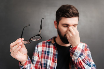 Tired man standing over chalkboard while massaging his nose
