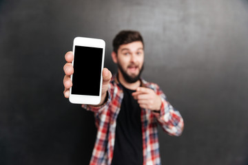 Smiling man holding and showing blank screen cell phone