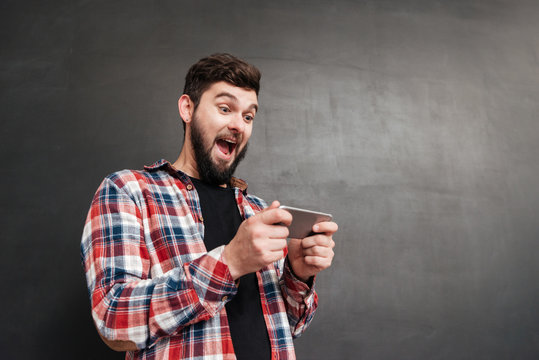 Excited man playing at phone over chalkboard