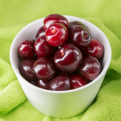 A cup of cherries on the green beach towel