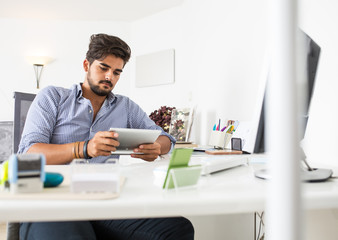 Portrait of male designer using  tablet in a bright office.