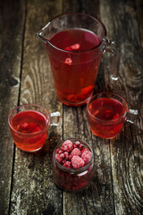 Berries compote in glass jar , two cup on wooden background. Selective focus.