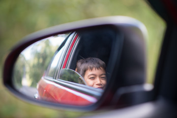 Mirror of little boy in the car while on drive