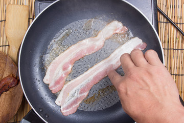 Chef frying bacon in the pan