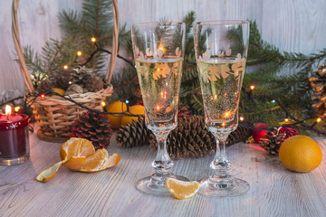 Christmas holidays: two glasses of champagne and christmas decorations on light wooden backgound