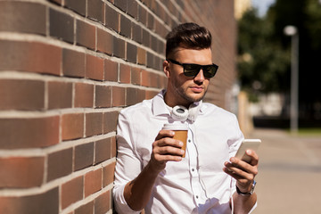 man with smartphone and coffee cup on city street