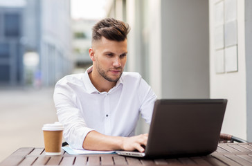 Fototapeta premium man with laptop and coffee at city cafe