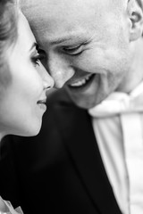 Groom smiles broad leaning to bride's tender face